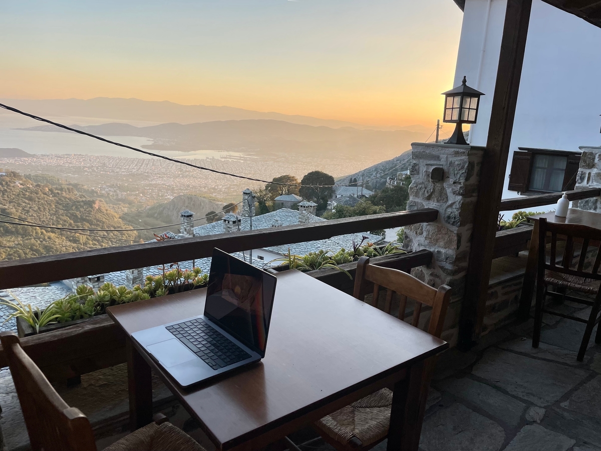 Patricks Lieblingsarbeitsplatz mit Laptop auf einem Balkon mit Aussicht auf ein Tal bei Sonnenuntergang